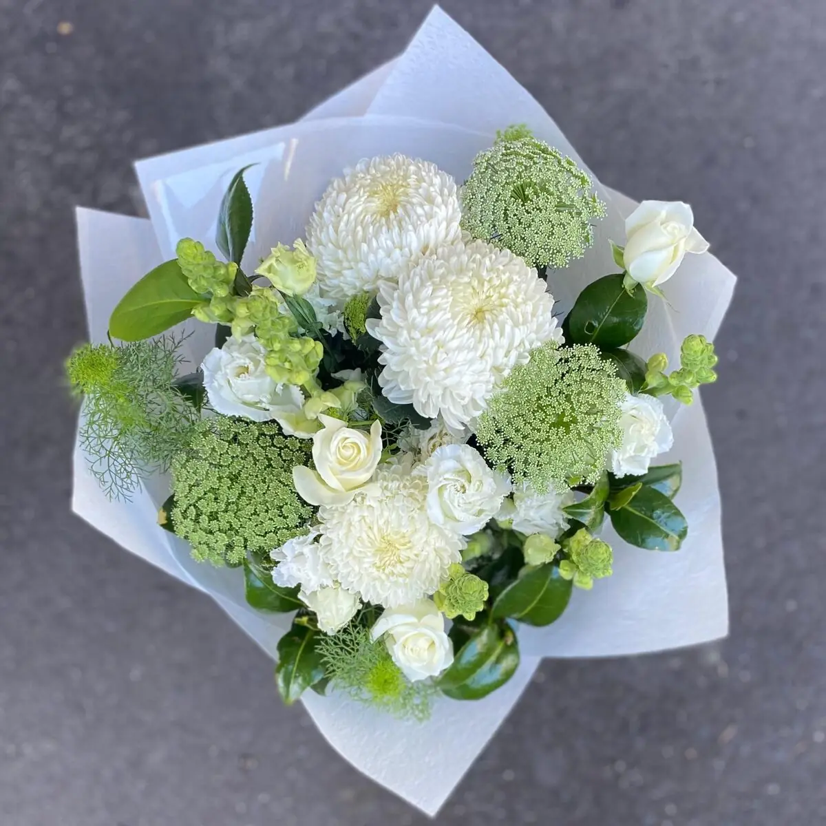 Hand-tied bouquet of white and green seasonal blooms in white wrap
